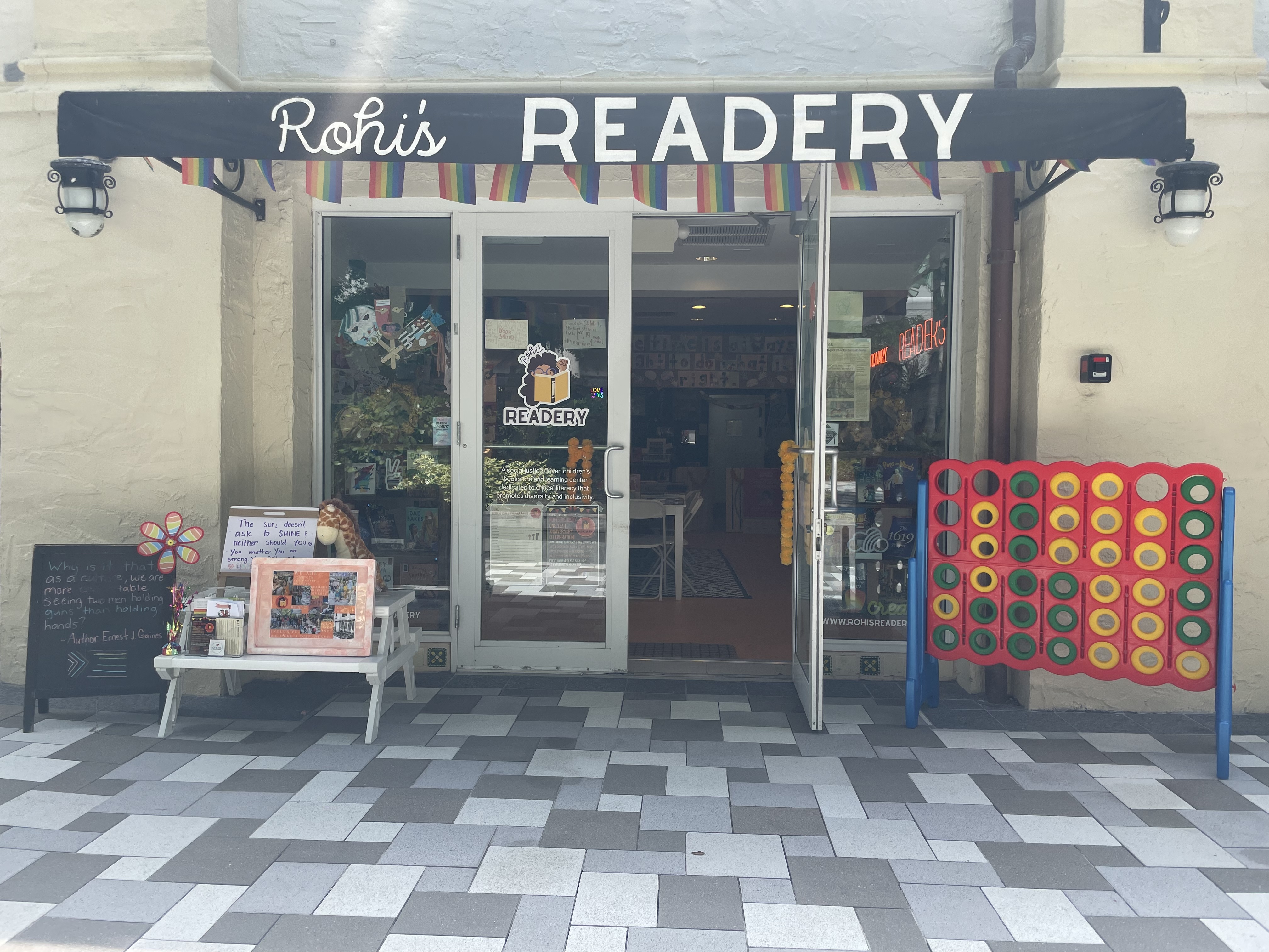 The entrace of Rohi's Readery. The door is propped open. A bench and giant connect four game sit outside. 