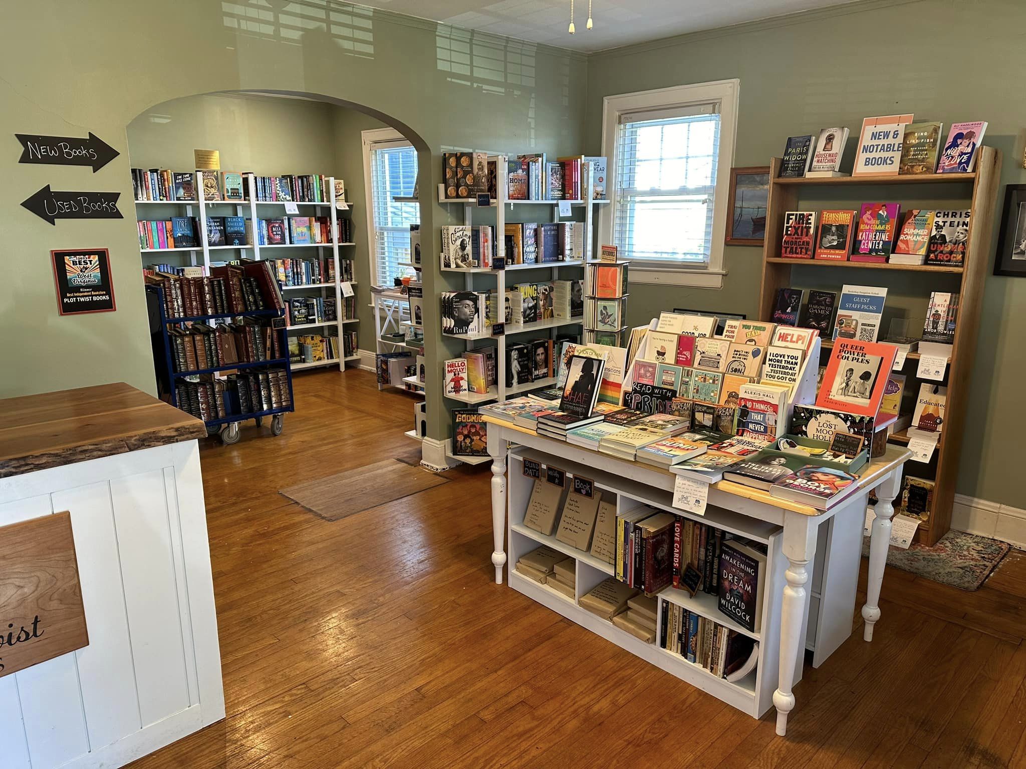 Bookshelves fill a room with green walls and a wood floor. 