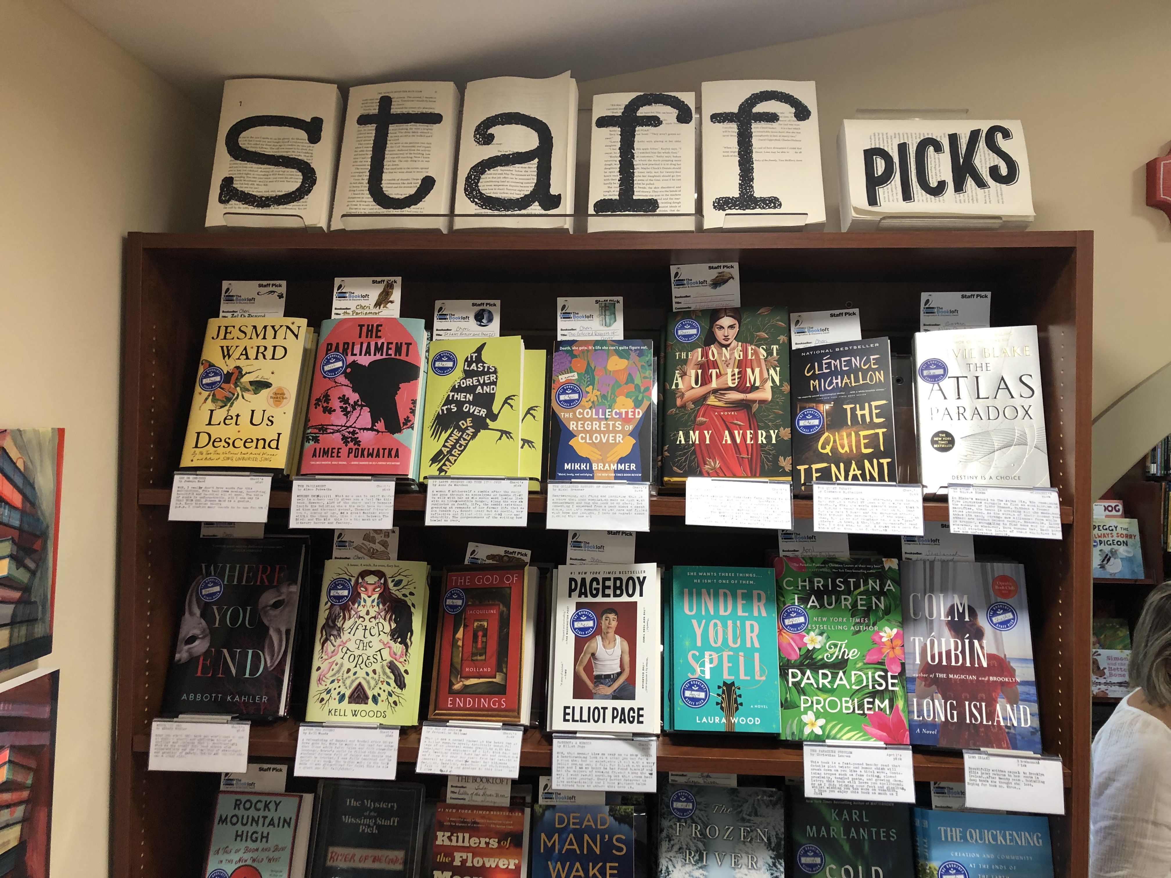 A staff picks display. Front facing books with shelf-talkers cover the bookshelf.